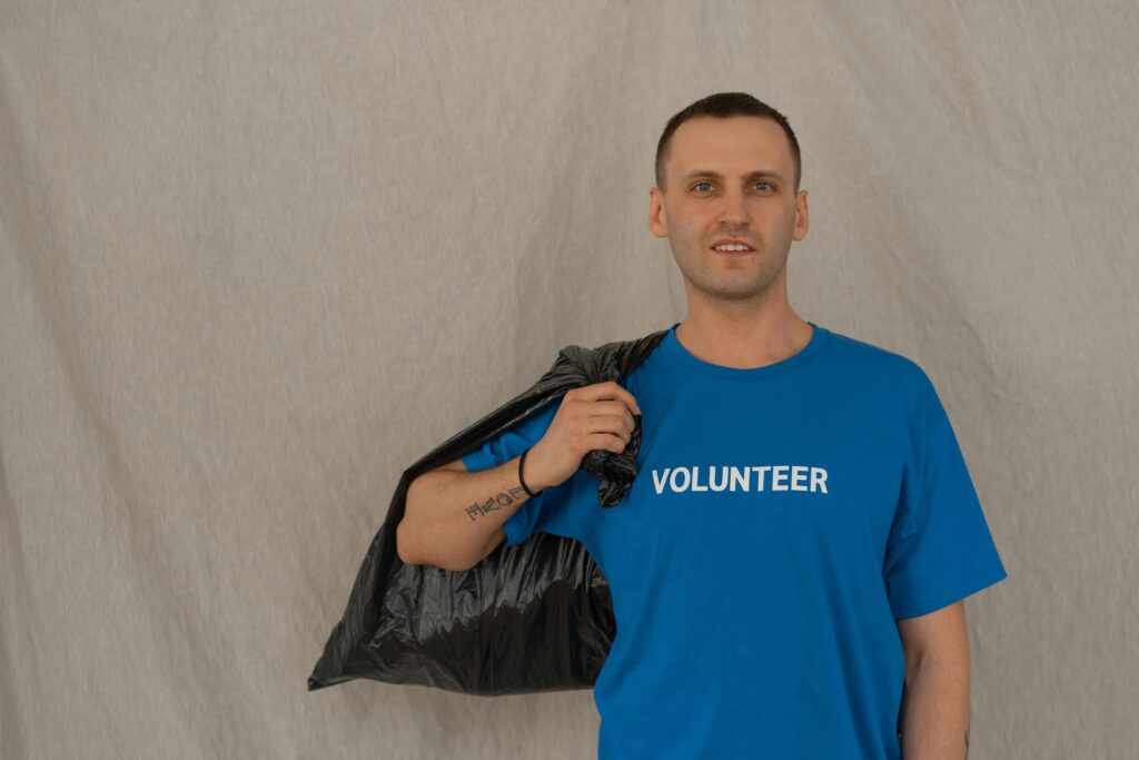 Volunteer in blue shirt holding a garbage bag during a cleanup effort.